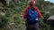 Traveler girl in cap with backpack climbing stones mountains. Back view