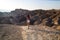 Traveler girl with fit body is standing in white short shorts in front of dry hot lifeless desert landscape, Zabriskie Point USA