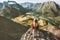 Traveler girl standing on cliff above mountains valley