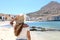 Traveler girl walking on the beach on Mediterranean sea island of Favignana. Back view of young woman holds hat and enjoying sight