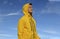 Traveler handsome man in yellow rain coat looking forward stay on vivid blue sky scenic view background empty copy space for your