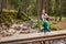 Traveler hiker with backpack crosses mountain river in Carpathian forest walking on bridge. Trip to summer Ukraine