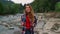 Traveler hiking along river in mountains. Smiling woman walking at river