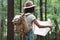 Traveler hipster woman in forest with backpack searching direction on map