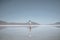 Traveler looking at Bonneville salt flat and mountain range reflecting in lake