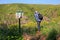 Traveler looks down of the rocky canyon edge. Tourist trail to Daliyot waterfalls. Warning sign in English, Hebrew and Arabic