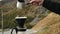 Traveler man making filter coffee and pours water in ground coffee beans against mountain view