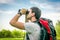 Traveler man with red backpack looks through a binoculars