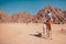 Traveler man rides a camel in desert by Sinai mountains. Boy bedouin guiding animal. Summer vacation