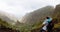 Traveler on the mountain edge making a photo of landscape. Deep clouds above green Xo-Xo Valley. Santo Antao Island