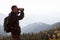 A traveler in the mountains looks in the binoculars