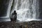 A traveler relaxing and bathing under a swift waterfall