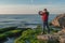 Traveler on a rocky seashore overgrown with green algae taking pictures