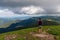 Traveler standing on high mountain cliff, enjoying scenery on mountain top. Pov view. Hiking freedom concept