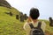 Traveler taking pictures of abandoned massive Moai statues scattered on Rano Raraku volcano, former Moai quarry on Easter Island