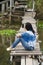 Traveler thai woman use smartphone portrait and selfie on the wooden brigde and travel Pakpra canal at Ban Pak Pra fishing village