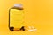 Traveler tourist suitcase trunk luggage bag with summer hat and sneakers on yellow orange background. Passenger