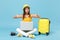 Traveler tourist woman in yellow casual clothes, hat with suitcase laptop pc photo camera isolated on blue background