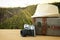 traveler vintage luggage, camera and fedora hat over wooden table infront of a field at sunset light.