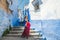 Traveler white young caucasian girl standing in Chefchaouen, the blue city, looking at the camera and posing for a picture,