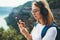 Traveler woman with hipser glasses holds mobile phone in hands and selects music for headphones via Internet technology to enjoy