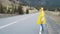 Traveler woman hitchhiking on a Cloudy road and walking. Young happy backpacker woman looking for a ride to start a