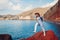 Traveler woman jumping on rock on Red beach on Santorini island, Greece. Traveling and vacation concept