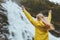 Traveler woman raised hands enjoying waterfall