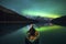 Traveler woman sitting on canoe with aurora borealis over Spirit Island in Maligne lake at Jasper national park, Alberta, Canada