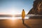 Traveler woman standing on empty beach in yellow raincoat alone travel lifestyle