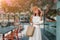 Traveler woman in white elegant outfit walking by the romantic streets of greek resort town with blooming Bougainvillea