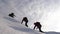 Travelers climb rope to their victory through snow uphill in a strong wind. tourists in winter work together as team
