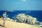 Travelers father and son with map in their hands stand on the edge of the rocky sea coast. Family travel concept