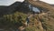 Travelers hiking at mountain path aerial. People at nature landscape. Mount top with snow, grass