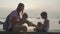 Travelers mother and daughter sits at seafront and drinks coconats in trip