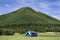 Travelers people build tent camping on grass field for rest and sleep near mountain