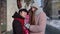 Travelers sisters holding younger sister child girl in hands, talking, smiling, embracing in city