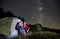 Travelers sitting in camp tent under night starry sky.