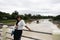 Travelers thai women take photo on small bridge crossing Sakae Krang river with view landscape water flowing and wooden ship