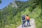 Travelers travel on the road in mountains go trekking together. Nature background. Group of tourists hitching a ride