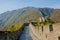 Travelers walk down walkway on top of famous Great Wall of China on sunny day