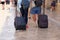 Travelers is walking with luggage on street, goes to city hotel. Tourists carry suitcases on wheels in sunny day. Active lifestyle