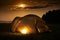 Traveling and camping concept - camp tent at night under a sky full of stars. Orange illuminated tent. Beautiful nature - field,