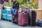 Traveling -Luggage piled up at an airport with someones foot resting on a bag and another unrecognizable customer sitting in a