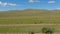 Traveling through open steppe fields and majestic Mongolian mountains. Rural countryside landscape with hills, blue sky with