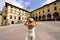 Traveling in Tuscany. Back view of tourist girl holding hat in Piazza Grande square in the historic town of Arezzo, Tuscany, Italy