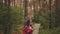 Traveling woman with dreadlocks with map in woods. Female traveler with backpack in woods reading map in cloudy weather