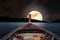 Traveling on wooden boat at night with full moon and stars on sky. romantic and scenic panorama with full moon on sea at night