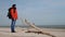 A traveling young man with a huge tourist backpack and wearing a bright red jacket and winter hat came up to the sea.