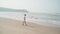 Traveling young man walking along sea coast. Male tourist promenading while resting on sandy beach near waving sea.